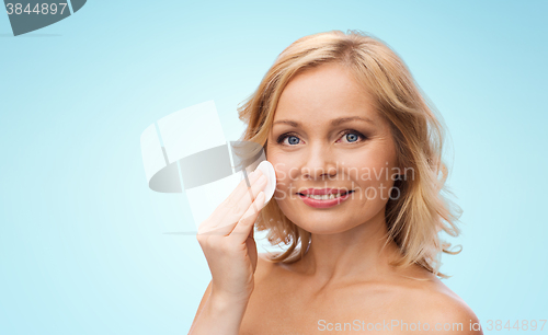 Image of happy woman cleaning face with cotton pad