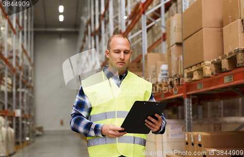 Image of man with clipboard in safety vest at warehouse