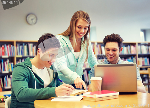 Image of happy students with laptop and books at library