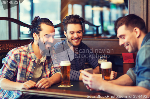 Image of male friends with smartphone drinking beer at bar