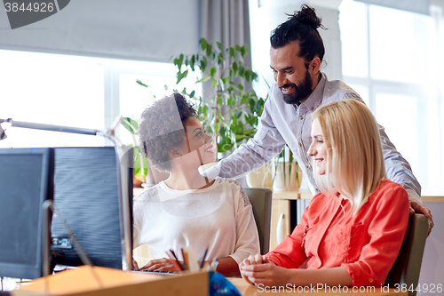 Image of happy creative team with computer in office