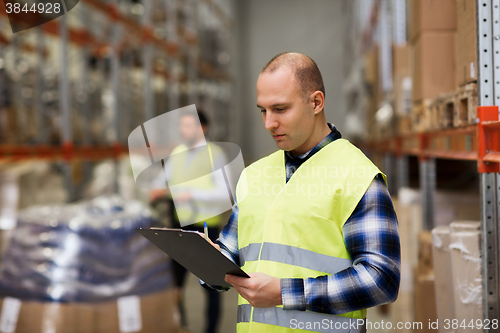 Image of man with clipboard in safety vest at warehouse