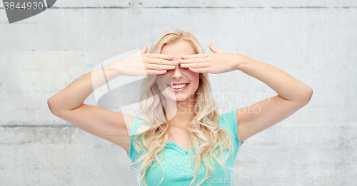 Image of smiling young woman or teen girl covering her eyes