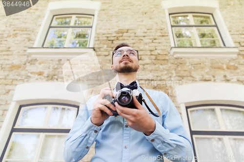 Image of happy young hipster man with film camera in city