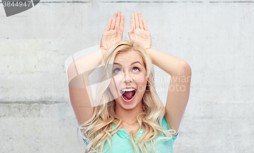 Image of happy smiling young woman making bunny ears