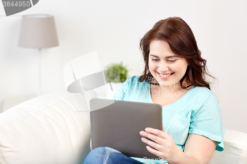 Image of happy young plus size woman with tablet pc at home