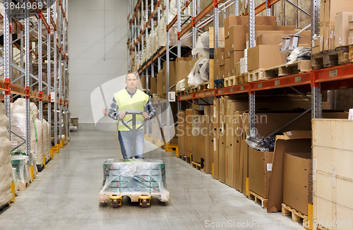 Image of man carrying loader with goods at warehouse