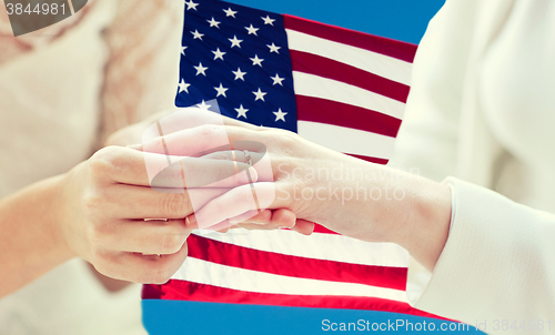 Image of close up of lesbian couple hands with wedding ring