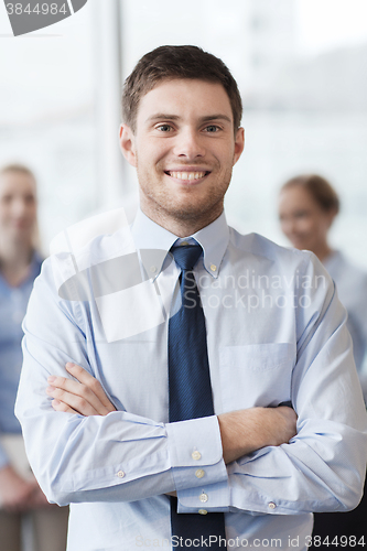 Image of smiling businessman with colleagues in office