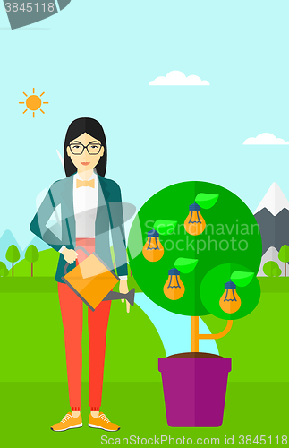 Image of Woman watering tree with light bulbs.