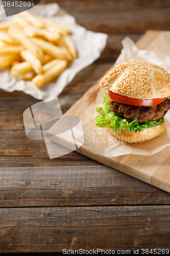 Image of Homemade hamburgers and french fries on wooden table