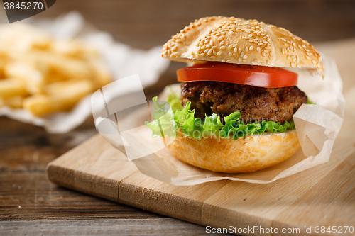 Image of Homemade hamburgers and french fries on wooden table