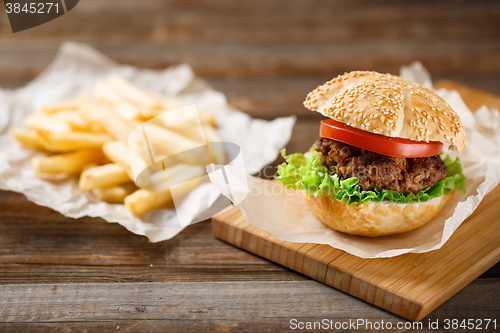 Image of Homemade hamburgers and french fries on wooden table