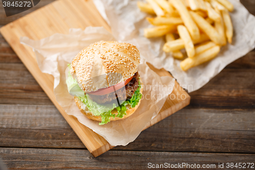 Image of Homemade hamburgers and french fries on wooden table