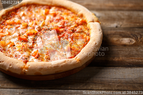 Image of Tasty pizza on old wooden table.