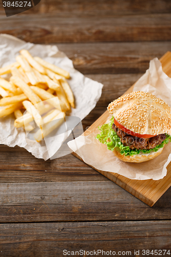 Image of Homemade hamburgers and french fries on wooden table