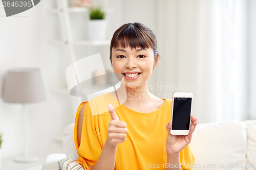 Image of happy asian woman showing smartphone at home