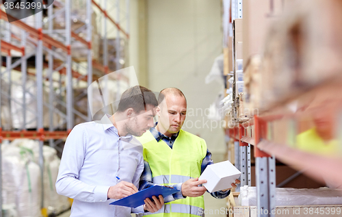 Image of worker and businessmen with clipboard at warehouse