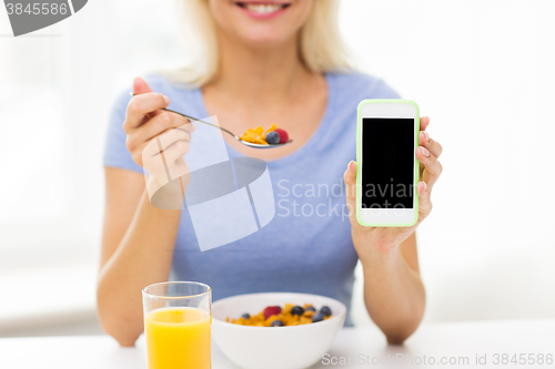 Image of close up of woman with smartphone eating breakfast