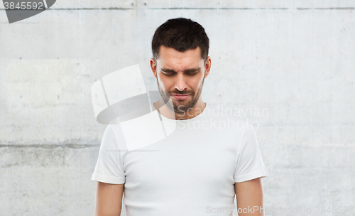 Image of unhappy young man over gray wall background