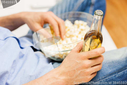 Image of close up of man with popcorn and beer at home