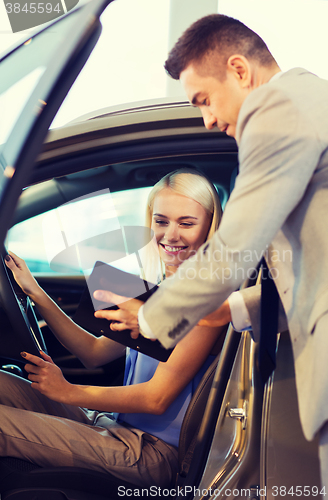 Image of happy woman with car dealer in auto show or salon