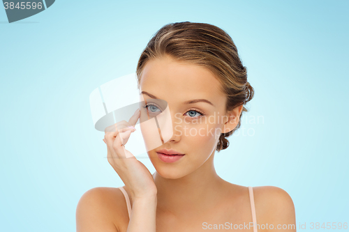 Image of young woman applying cream to her face