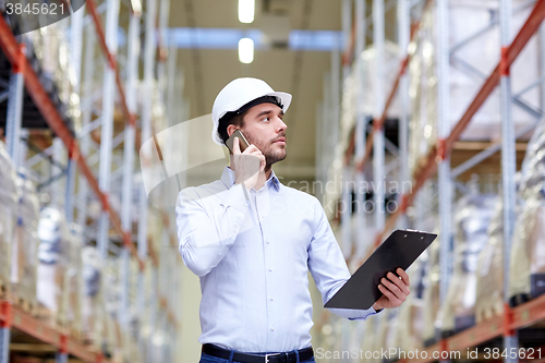 Image of man with clipboard and smartphone at warehouse