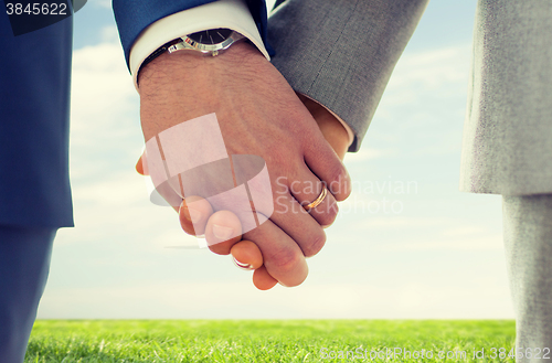 Image of close up of male gay hands with wedding rings on