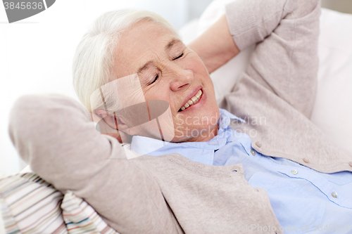 Image of happy senior woman resting on sofa at home