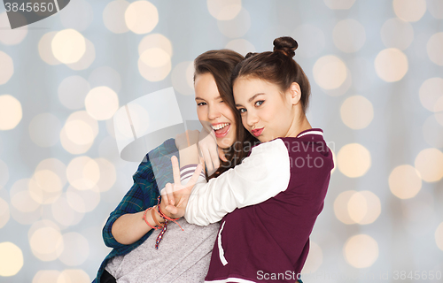 Image of happy teenage girls hugging and showing peace sign