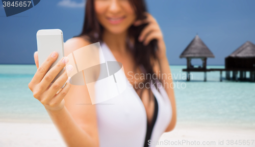 Image of young woman taking selfie with smartphone