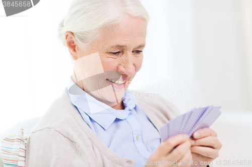 Image of happy senior woman playing cards at home