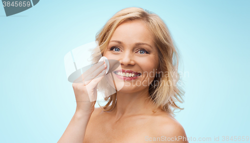 Image of happy woman cleaning face with cotton pad