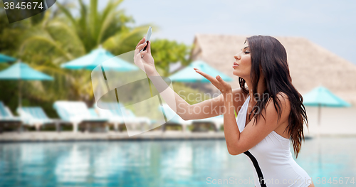 Image of young woman taking selfie with smartphone