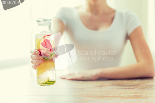 Image of close up of woman with fruit water in glass bottle