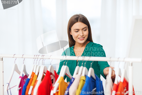 Image of happy woman choosing clothes at home wardrobe