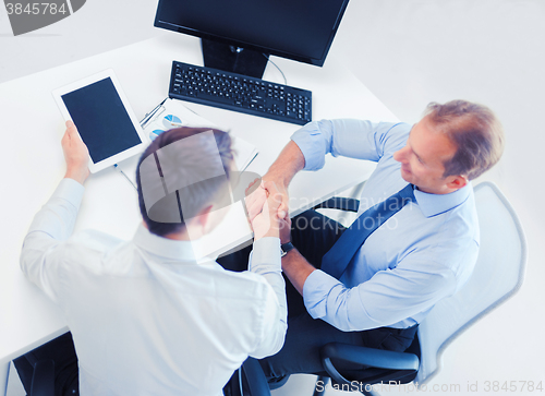 Image of businessmen shaking hands in office