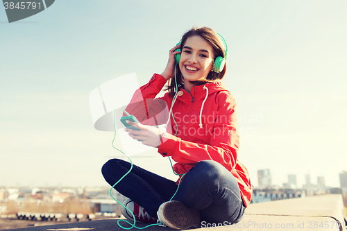 Image of happy young woman with smartphone and headphones