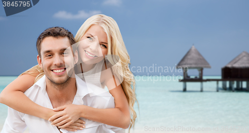 Image of happy couple having fun over beach with bungalow