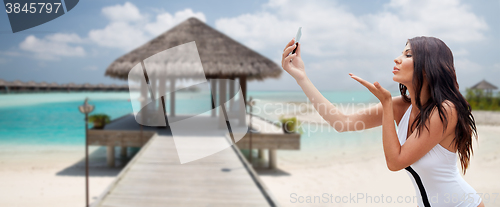 Image of young woman taking selfie with smartphone