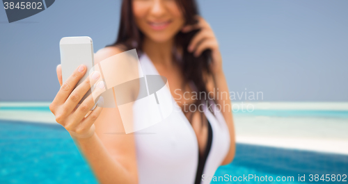 Image of young woman taking selfie with smartphone