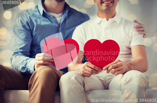 Image of close up of happy gay male couple with red hearts