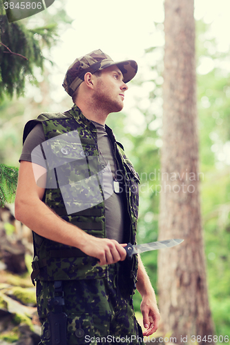 Image of young soldier or hunter with knife in forest