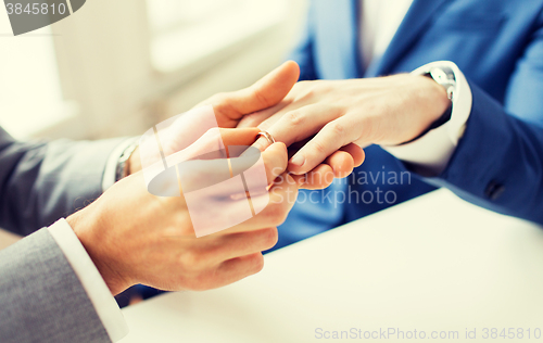 Image of close up of male gay couple hands and wedding ring