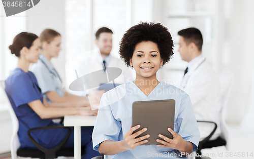 Image of happy doctor with tablet pc over team at clinic