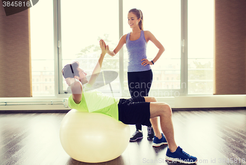 Image of smiling man and woman with exercise ball in gym