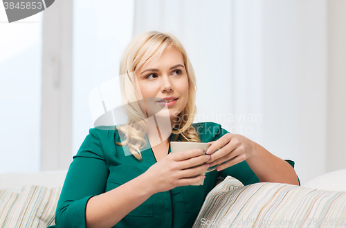 Image of happy woman  with cup of tea or coffee at home