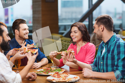 Image of friends eating pizza with beer at restaurant