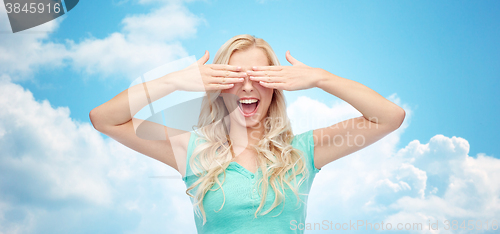 Image of smiling young woman or teen girl covering her eyes